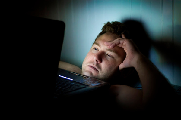 Man tired looking at a screen in bed